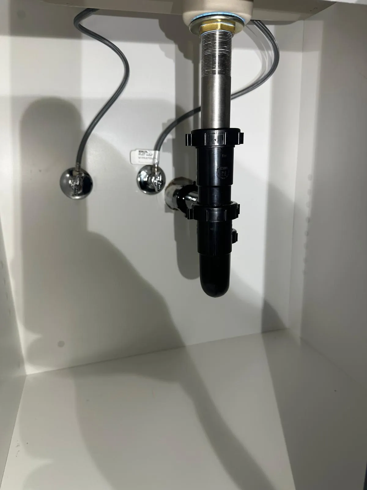Newly fitted P-trap and supply lines under a kitchen sink cabinet